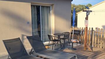 A deck with lounge chairs, a table, and a blue umbrella.