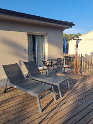 Una terraza con sillones de descanso, una mesa y una sombrilla azul.
