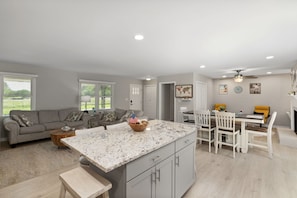 A spacious living area with a kitchen island, a dining table with chairs, and a sofa. - One Love | 3BR Home · Fenced Yard · Near I-95 (Smithfield)
