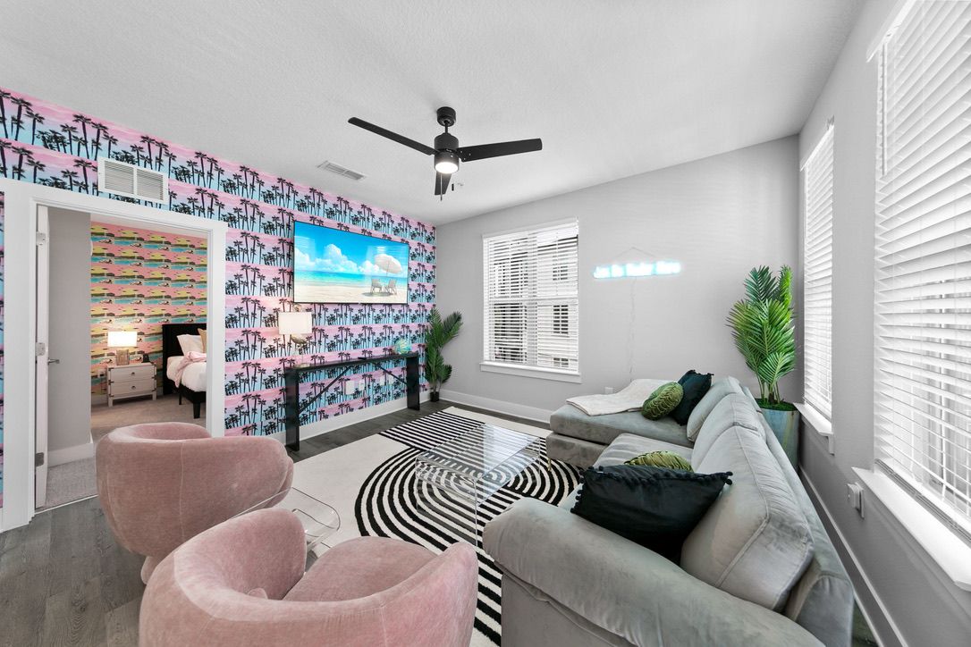 A modern living room with a sofa, chairs, a TV, and a patterned wall.