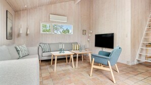 Un salon confortable avec un canapé, une table basse, un téléviseur et un fauteuil.