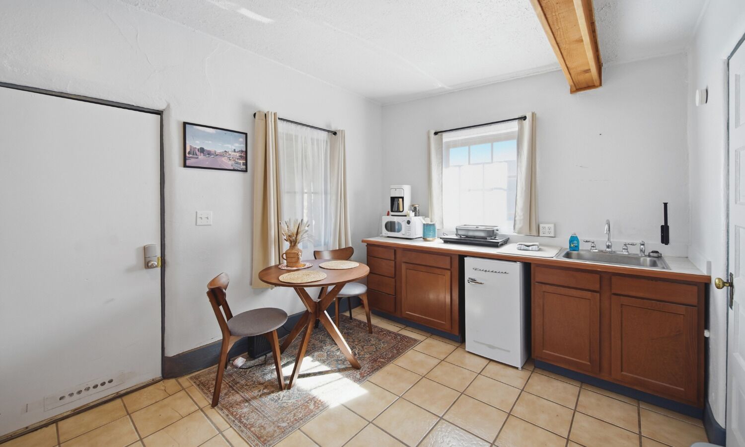 A compact kitchen with wooden cabinets, a built-in microwave, a coffee maker, and a sink.