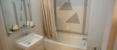Une salle de bain avec une baignoire, un lavabo, des toilettes et un miroir.
