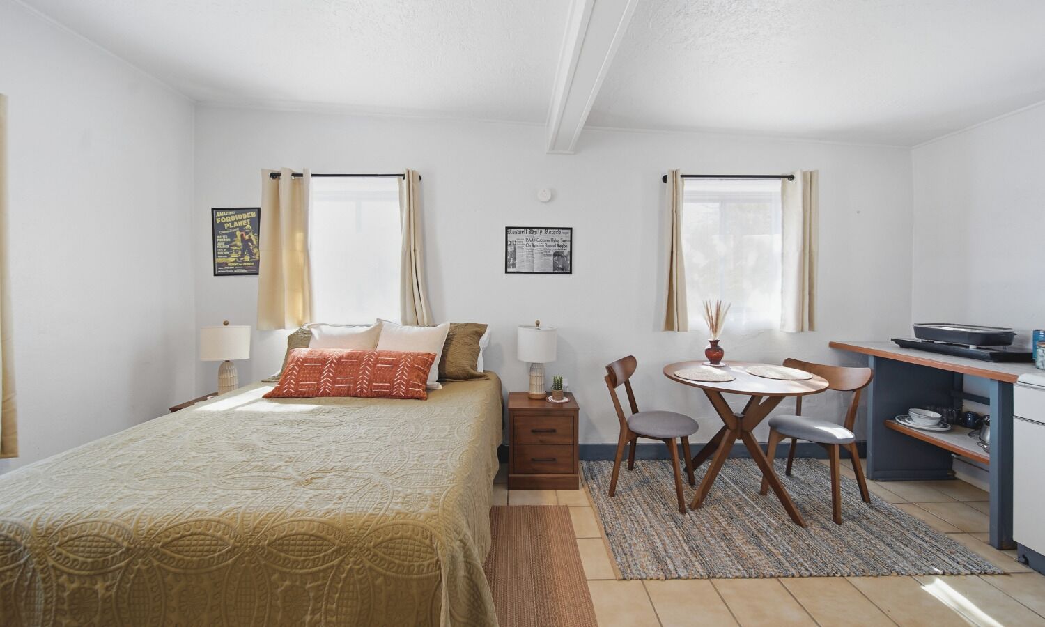 Una habitación de hotel compacta con una cama, un escritorio pequeño, una silla y una mesa de comedor.