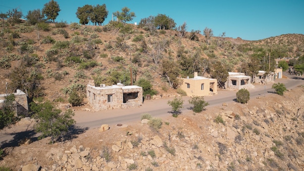 A rural landscape with several stone buildings, a dirt road, and sparse vegetation. - Dam Site Casitas (Truth or Consequences)