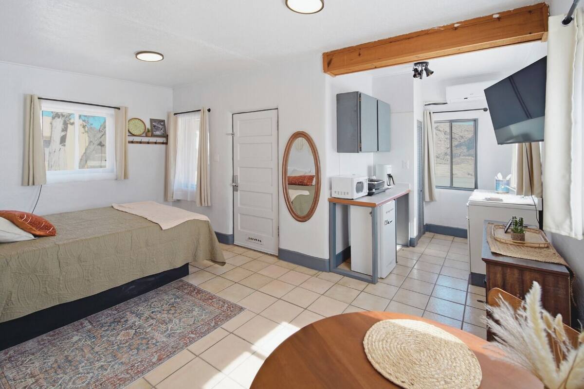 A hotel room with a bed, a desk, a television, and a small kitchenette.
