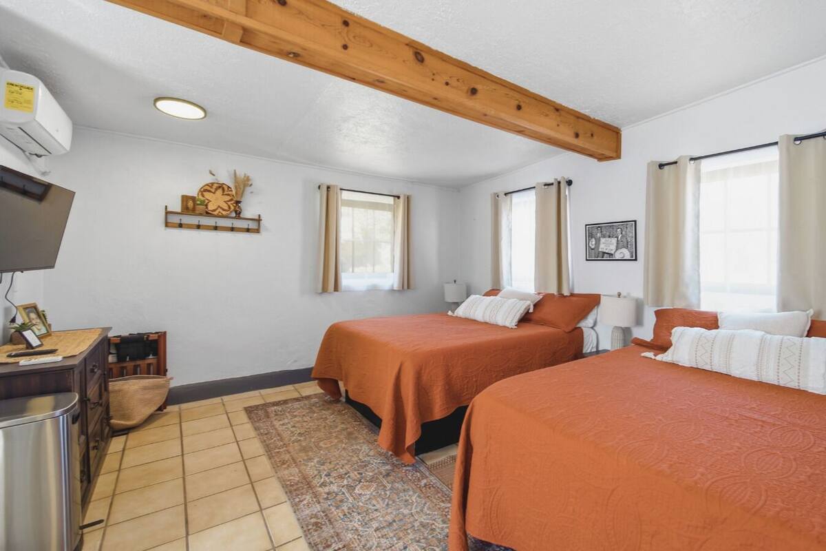 A hotel room with two beds, a television, a desk, and a window.