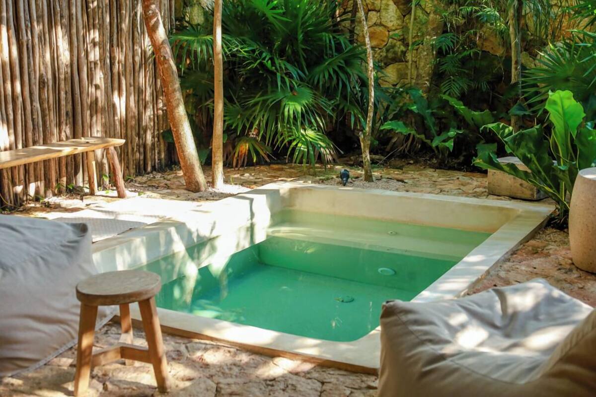 A rectangular hot tub surrounded by natural vegetation and a wooden deck.