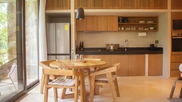 A modern kitchen with wooden cabinets, a black countertop, and a dining area with a round wooden table and chairs.