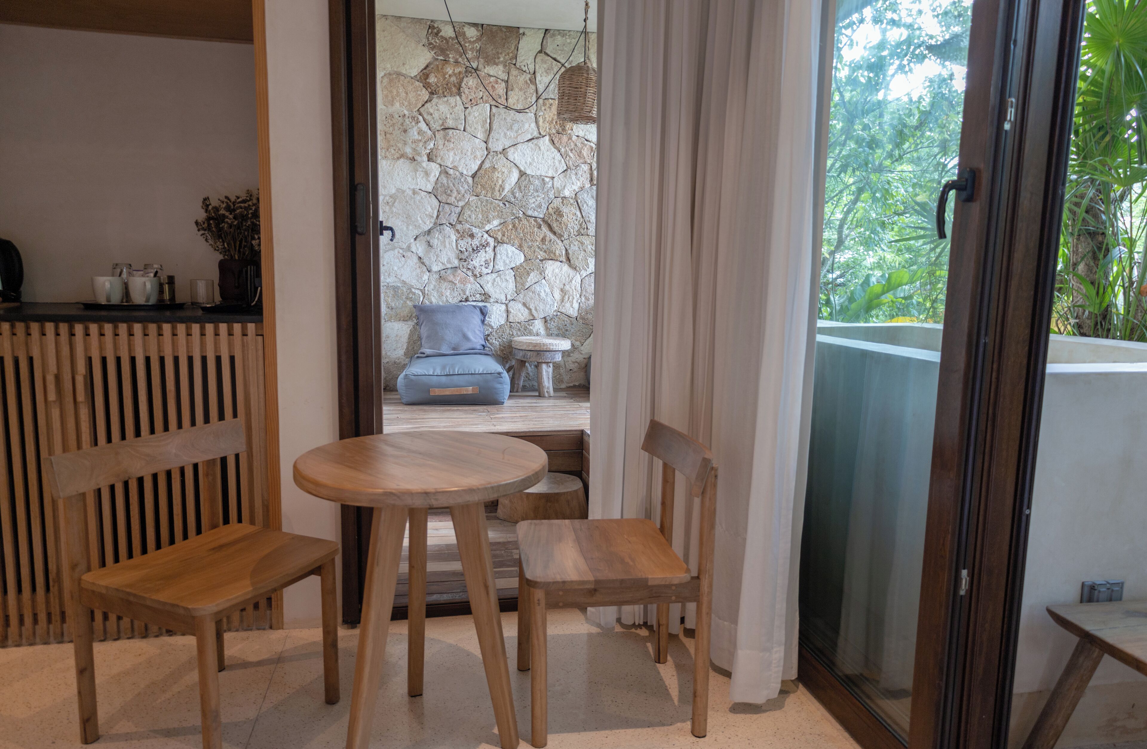 Un juego de comedor de madera con una pared de piedra y vistas a la vegetación.