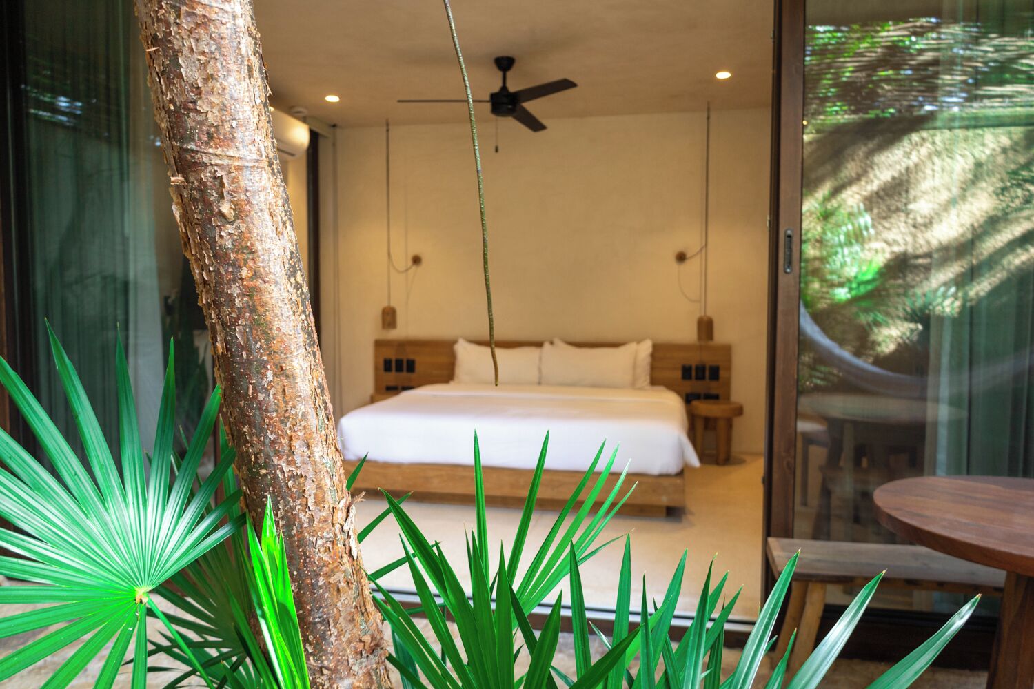 A bedroom with a bed, bedside tables, a ceiling fan, and a large window.