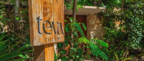 A wooden sign with the text "tev" and "TULUM".