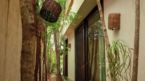 A narrow corridor with a naturalistic design, including a hanging basket and lush greenery. - TEVA TULUM (Tulum)