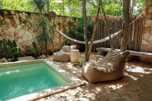 A pool area with a stone wall, a hammock, and a seating area with cushions. - TEVA TULUM (Tulum)