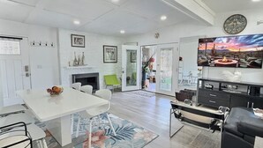Een ruime woonkamer met een open haard, een eettafel en een moderne entertainmentkast.