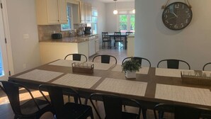 A dining area with a long table, black chairs, and a clock on the wall.
