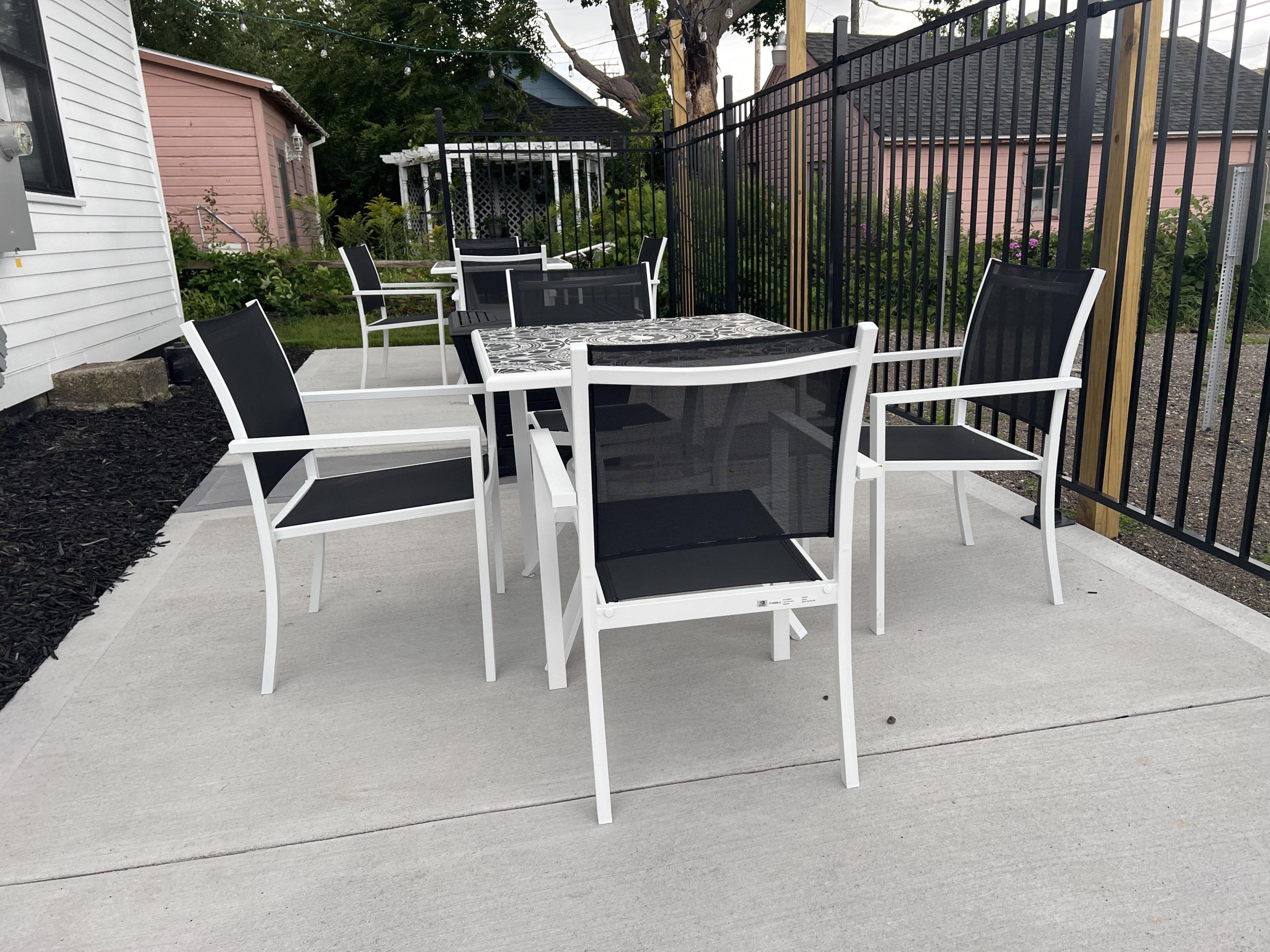 An outdoor patio with a table and chairs, a pergola, and a fence.