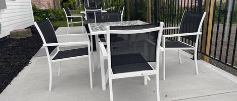 An outdoor patio with a table and chairs, a pergola, and a fence.