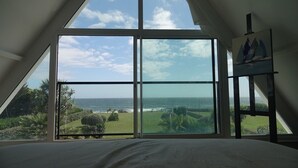 A bedroom with a large window overlooking a beach and ocean. - Villa "La Loubine" contemporary thatched cottage facing the sea (Batz-sur-Mer)