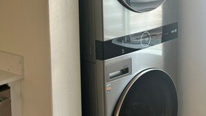 Vue de face d’un appareil combiné lave-linge et sèche-linge, avec un panneau de commande et une fenêtre circulaire sur le sèche-linge.