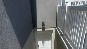 Un escalier menant à une porte blanche, au-dessus de laquelle est fixée une caméra de surveillance.