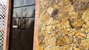 Un muro de piedra con un letrero que dice "CASA BRISA" y una puerta metálica con un picaporte.