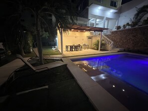 Une piscine avec un mur en pierre et des chaises longues.