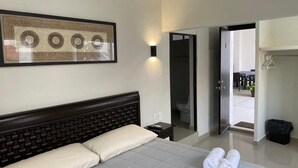 Habitación de hotel con una cama grande, una mesita de noche, una lámpara de pared, un cuadro enmarcado y una puerta que da a un balcón.