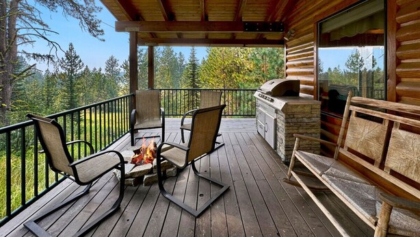 A wooden deck with outdoor seating, a stone fireplace, and a stone barbecue grill. - Rustic Cabin with Modern Comforts! (Cascade)