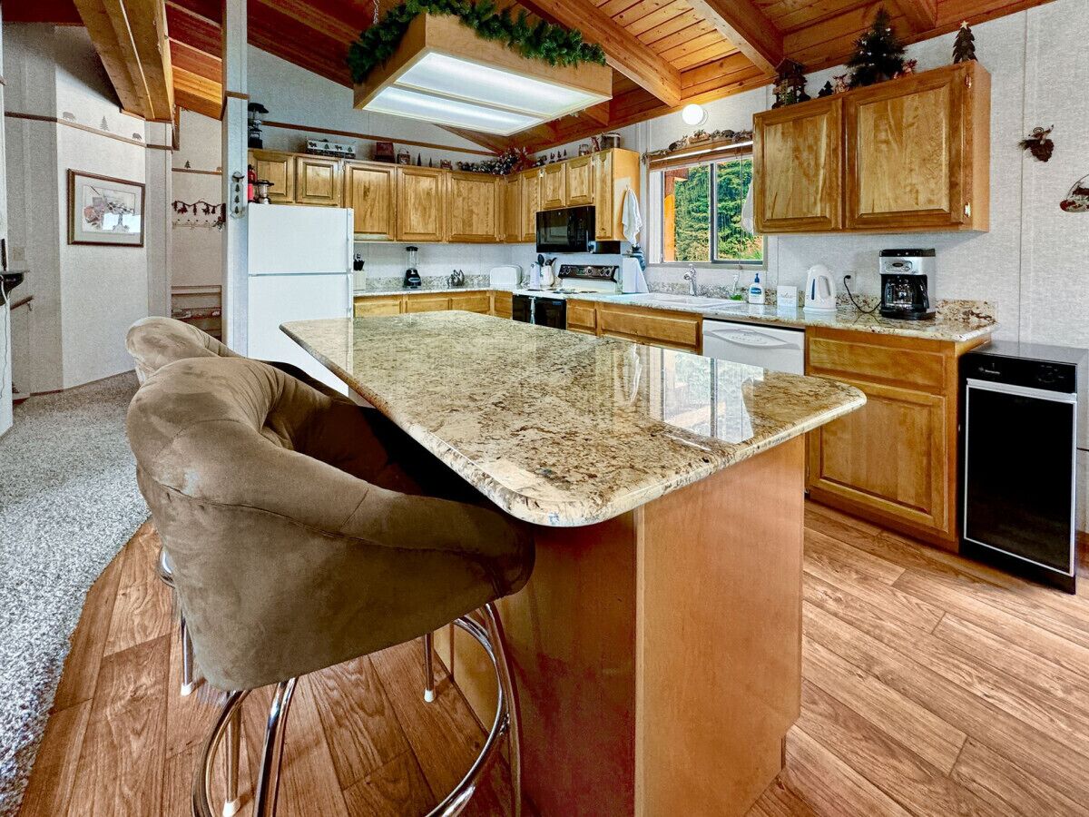 A kitchen with wooden cabinets, a granite countertop, and a bar stool.
