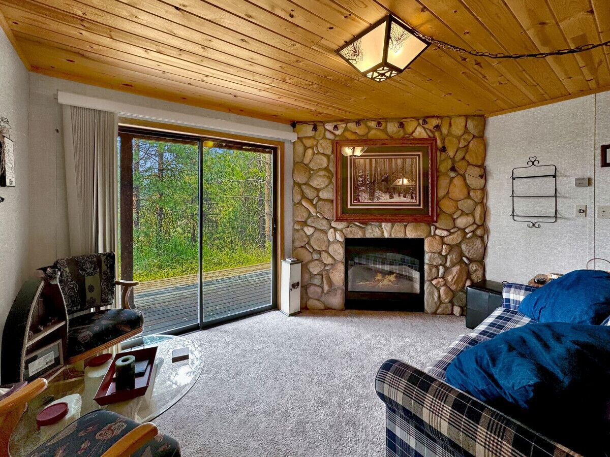 A cozy living room with a stone fireplace, a sofa, a coffee table, and a fireplace screen.