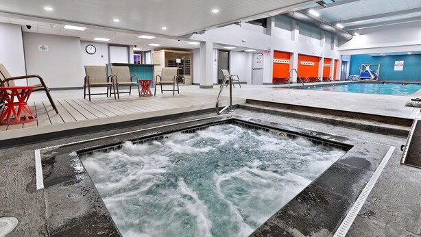 Un espace piscine comprenant un jacuzzi, des sièges et un comptoir d’accueil.