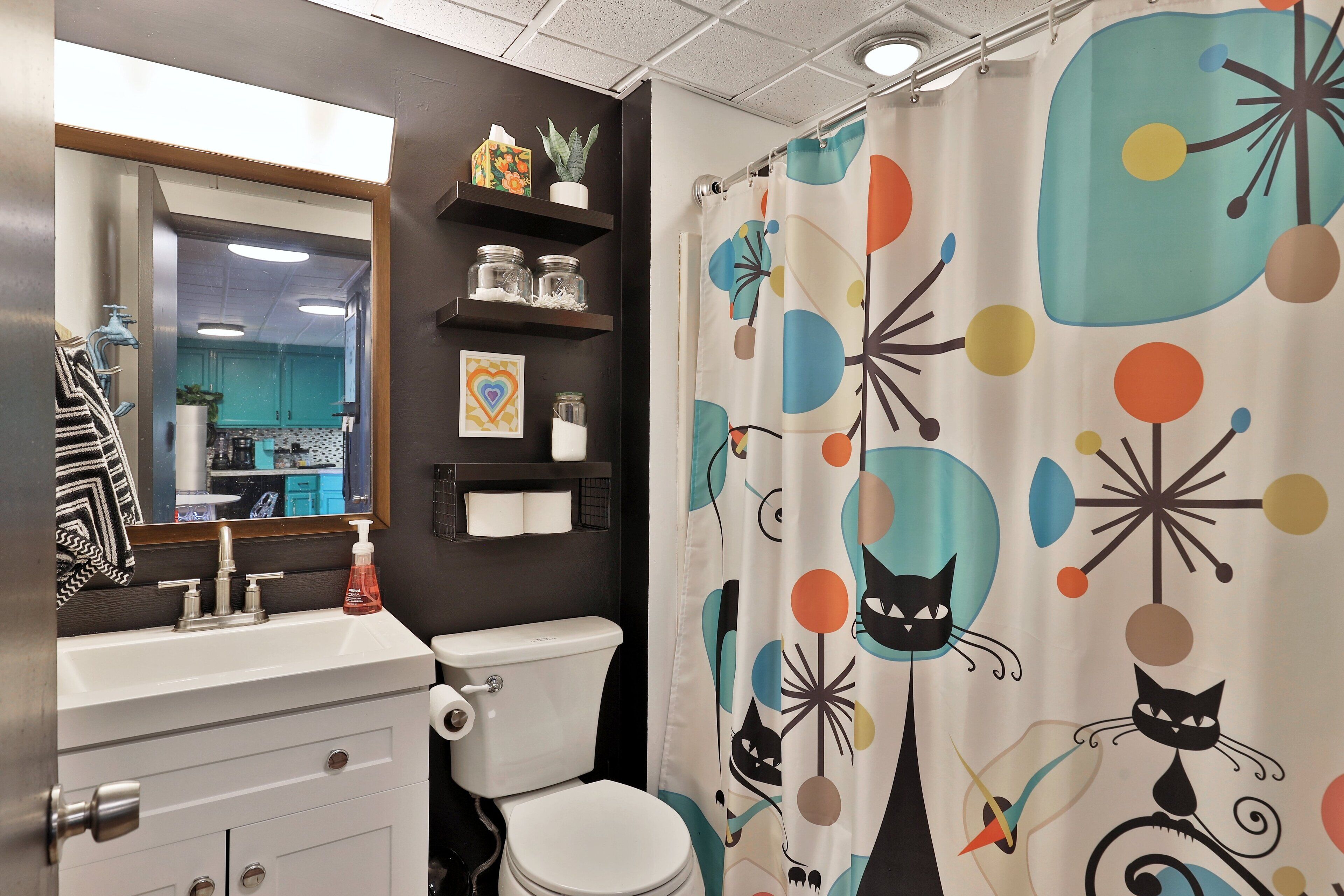 A bathroom with a white sink, a toilet, and a shower curtain with a colorful abstract pattern.