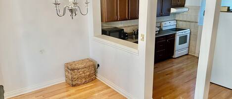 A kitchen with wooden cabinets, a stove, and a microwave. There is a wicker basket and a chandelier.