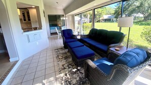 A spacious living area with a large window, a ceiling fan, and a view of the outdoors. - Tranquil Lake view 2 Bedroom 2 bath Villa in Myrtle Trace (Venice)