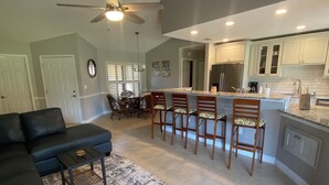 A modern kitchen with white cabinets, a large island, and a dining area with chairs. - Tranquil Lake view 2 Bedroom 2 bath Villa in Myrtle Trace (Venice)