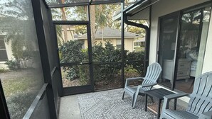A covered patio with a patterned rug, two chairs, and a table. - Tranquil Lake view 2 Bedroom 2 bath Villa in Myrtle Trace (Venice)