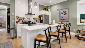 A modern kitchen with white cabinetry, stainless steel appliances, and a central island with bar stools.