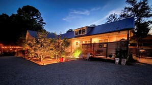 A modern house with a gravel driveway, a wooden deck, and a well-lit garden area.