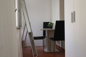 A room with a desk, two chairs, a potted plant, and a sliding door.
