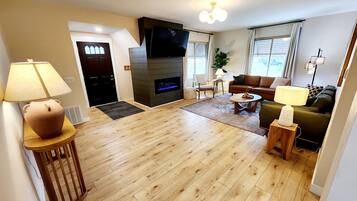 A modern living room with a fireplace, a sofa, a coffee table, and a TV.