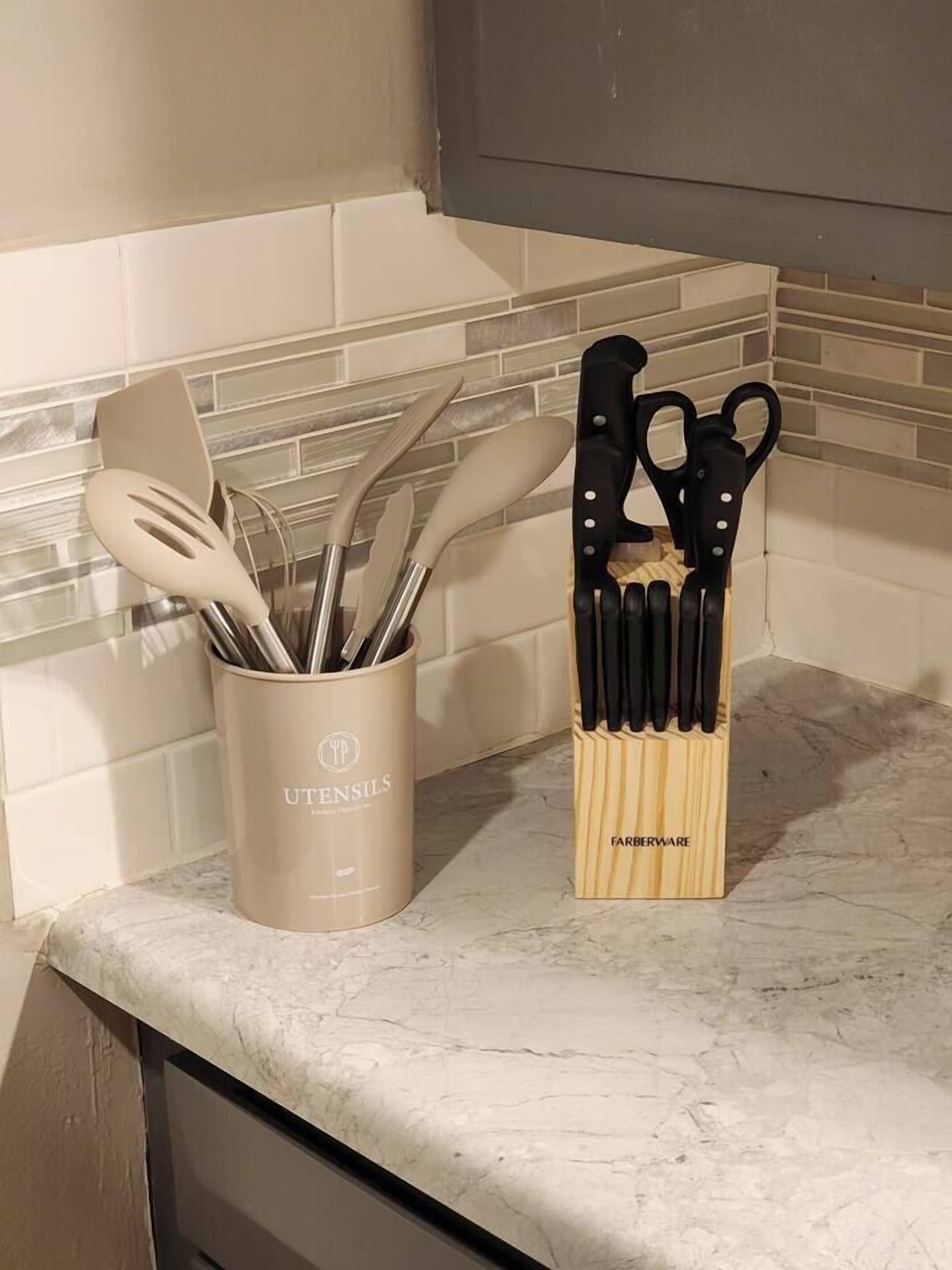 Un plan de travail de cuisine avec un porte-ustensiles contenant divers outils de cuisine et un bloc à couteaux.