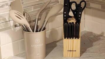 Un plan de travail de cuisine avec un porte-ustensiles contenant divers outils de cuisine et un bloc à couteaux.