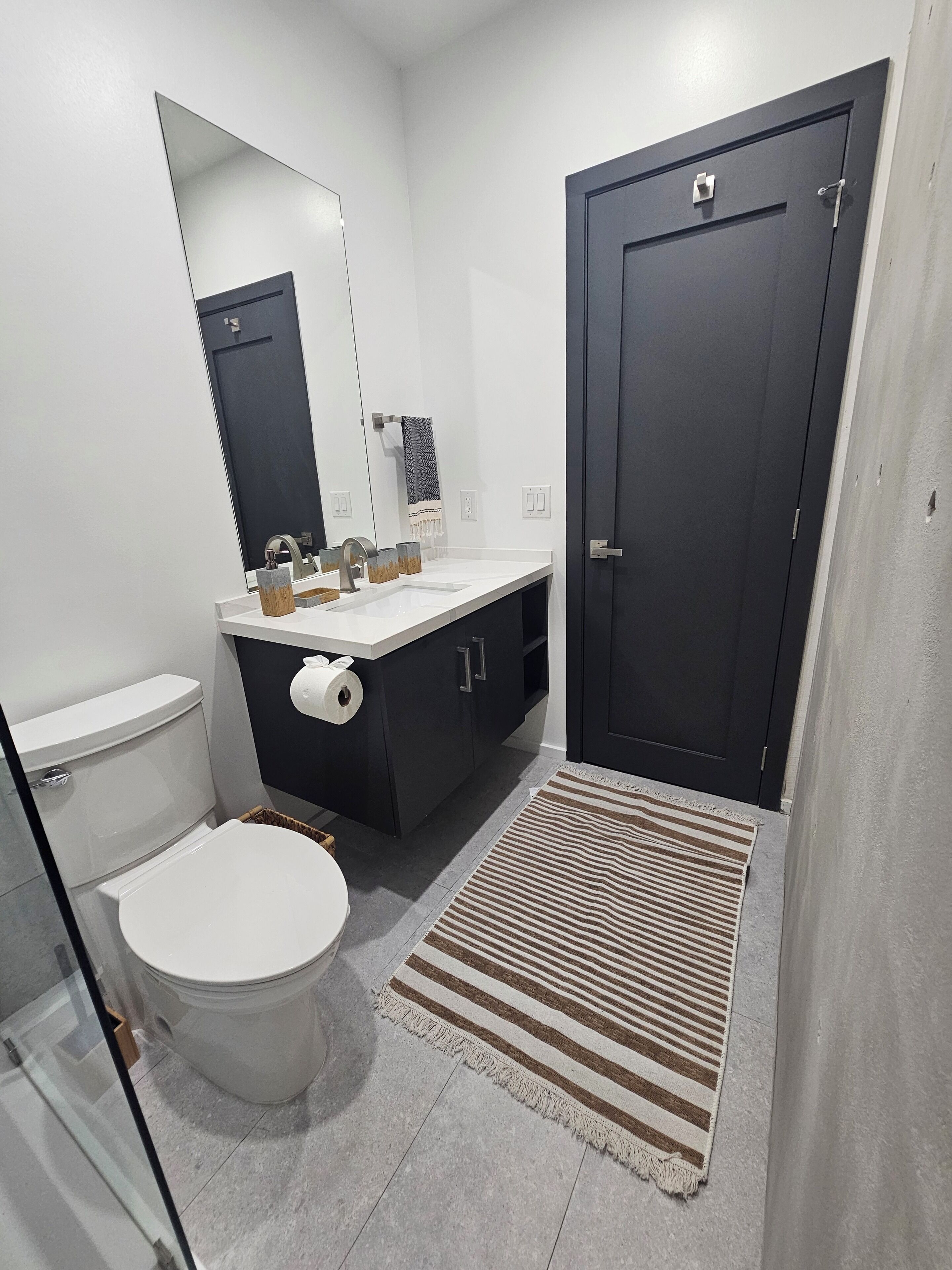 Une salle de bain moderne avec des toilettes, un lavabo et une porte sombre.