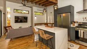 Eine moderne Küche mit Kochinsel, Barhocker, Backofen und großem Kühlschrank.
