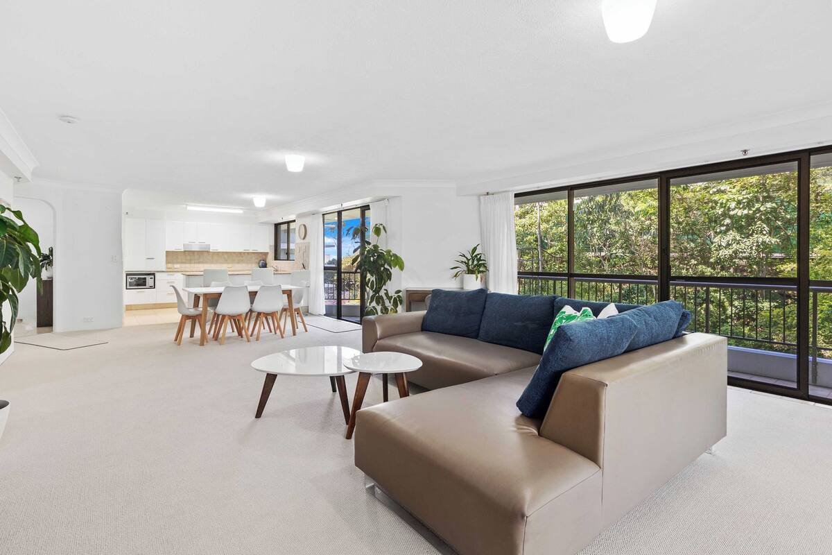 A modern living room with a sofa, coffee table, and dining area.