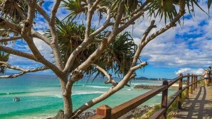 A coastal walkway with a wooden railing, palm trees, and a view of the ocean. - Burleigh Headland 2 Bedroom Stay, just a stones throw from the beach! (Burleigh Heads)