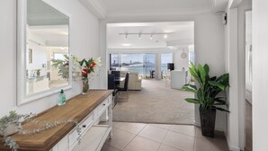 A spacious hallway with a view of the city skyline and ocean, leading to a dining area with a table and chairs. - Burleigh Headland 2 Bedroom Stay, just a stones throw from the beach! (Burleigh Heads)