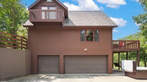 A two-story wooden house with a garage, a balcony, and a deck. - Private 4.5-Acre Retreat featuring Hot Tub-Firepit-Walk to Table Rock-Free Daily Attraction Tickets (Lampe)
