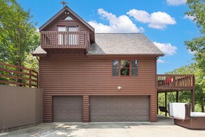 Une maison en bois à deux étages, dotée d’un garage, d’un balcon et d’une terrasse.